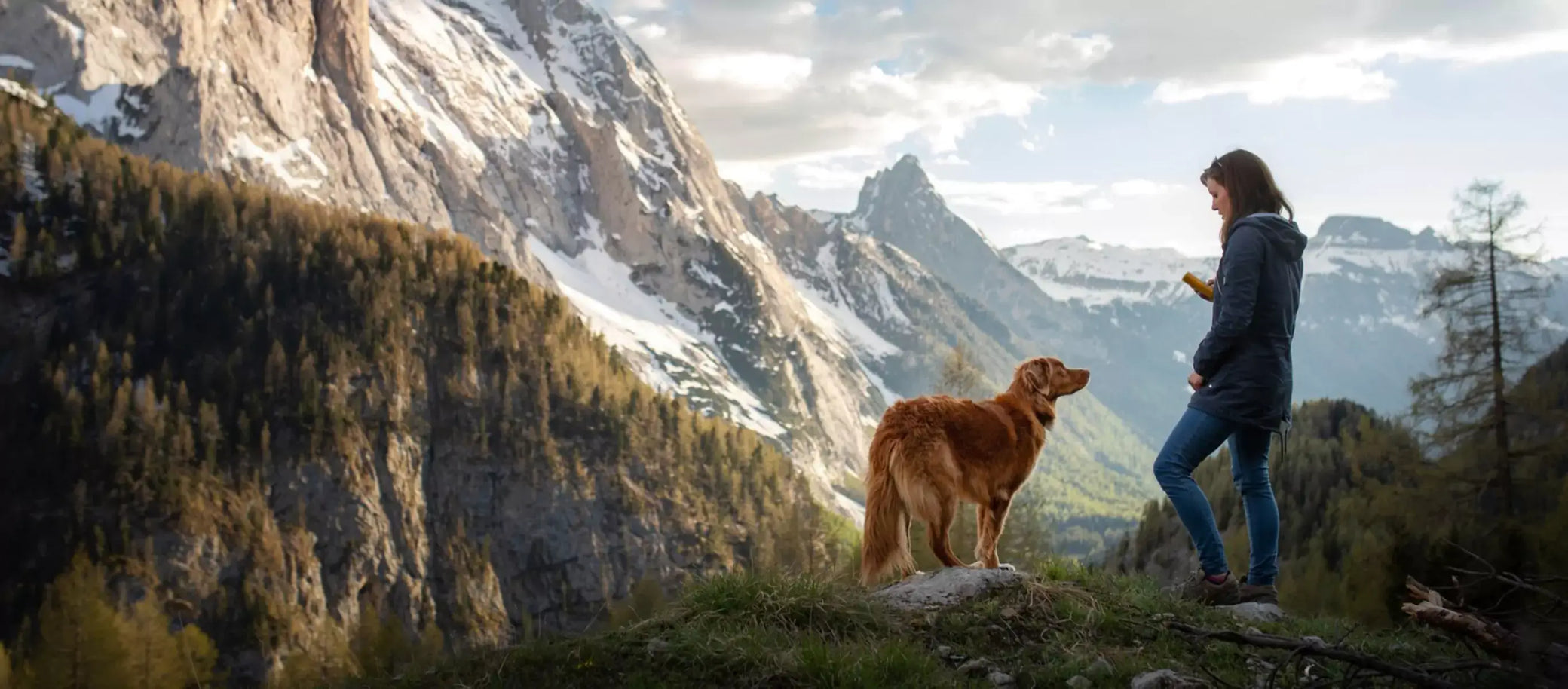 Woman and dog hiking in mountains